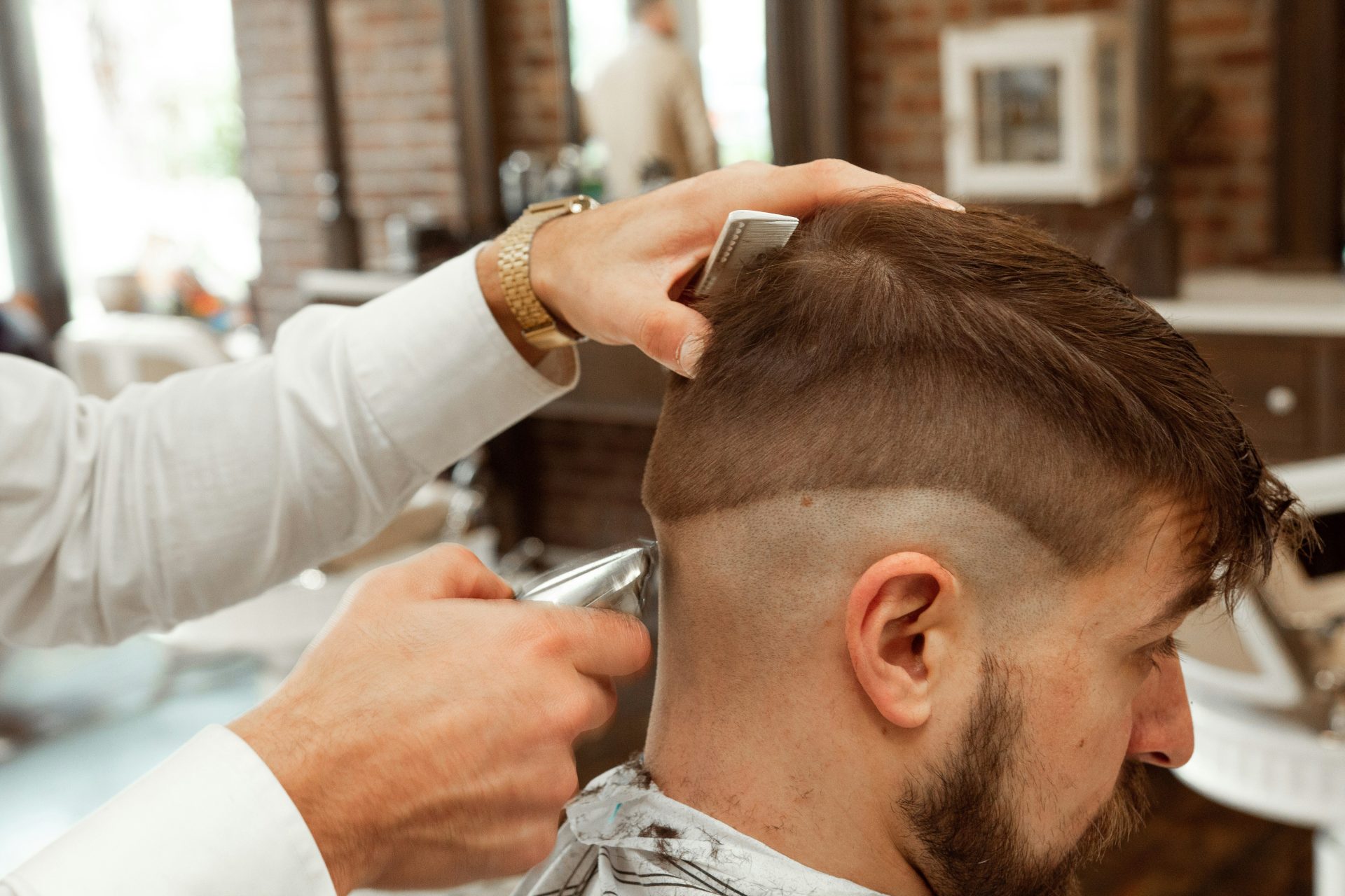 homme en chemise blanche coupant les cheveux d'un homme
